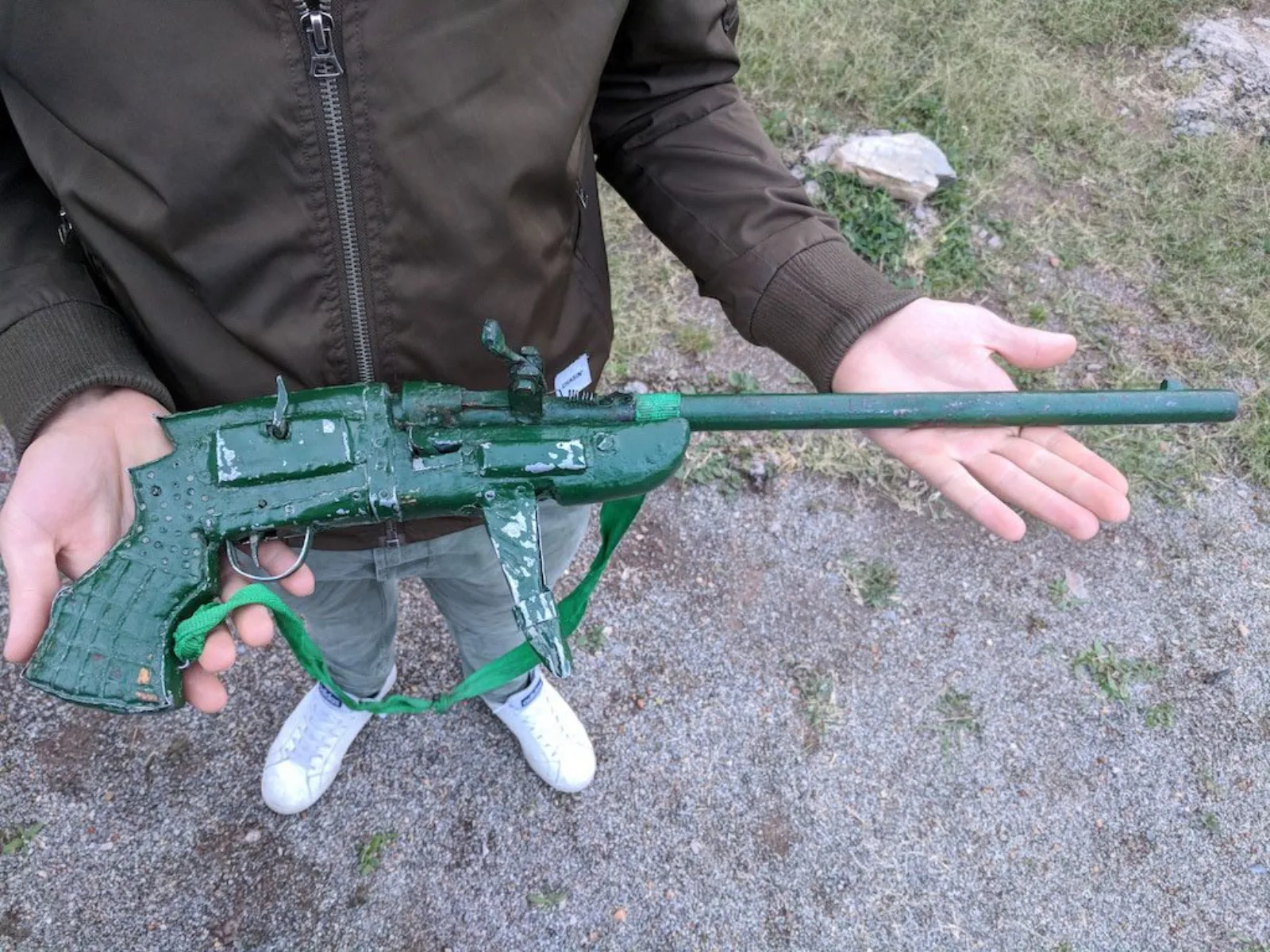 A self-made shotgun forged by poachers — bright green, with a trigger made from a Coca-Cola can